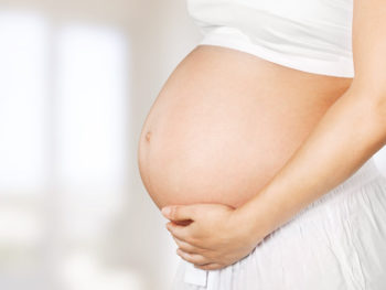 Pregnant woman holding her exposed belly