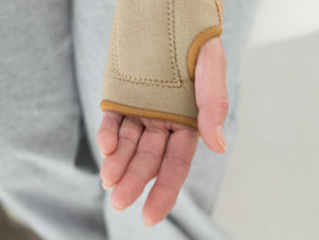 Close-up mid section of a woman with hand in wrist brace at the medical office